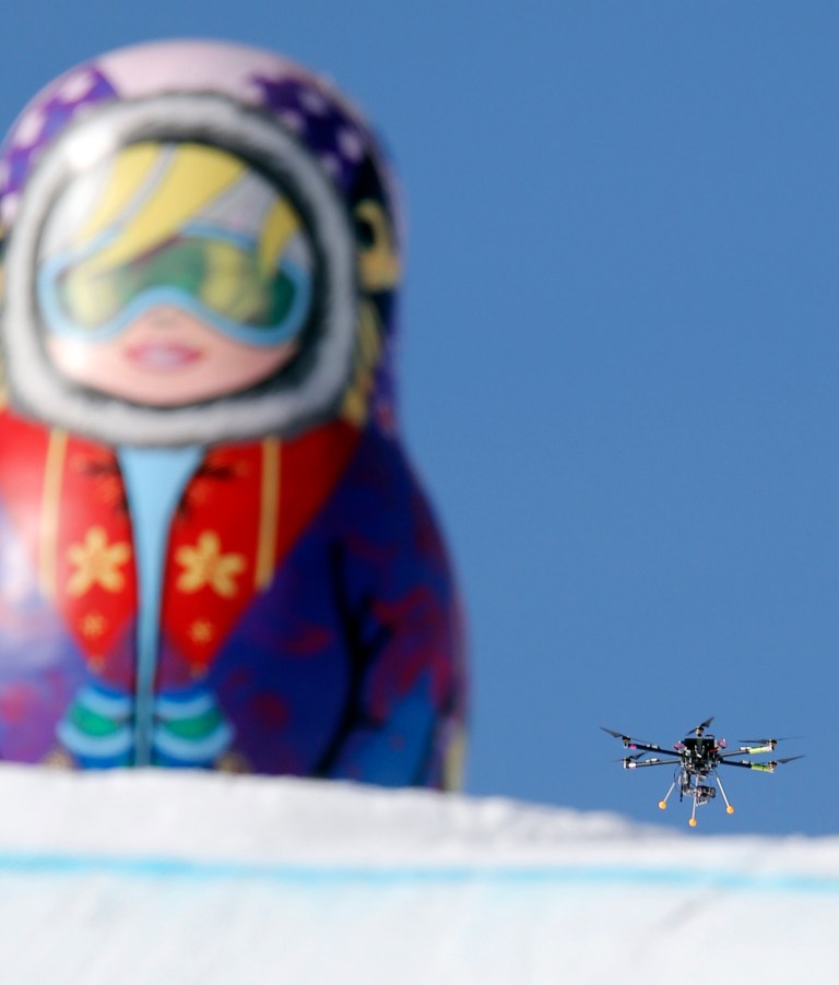 In this Friday Feb. 7 photo, a drone camera  flies about the slopestyle course during a freestyle skiing slopestyle training session at the Rosa Khutor Extreme Park ahead of the 2014 Winter Olympics, Friday, Feb. 7, 2014, in Krasnaya Polyana, Russia. (AP Photo/Sergei Grits)