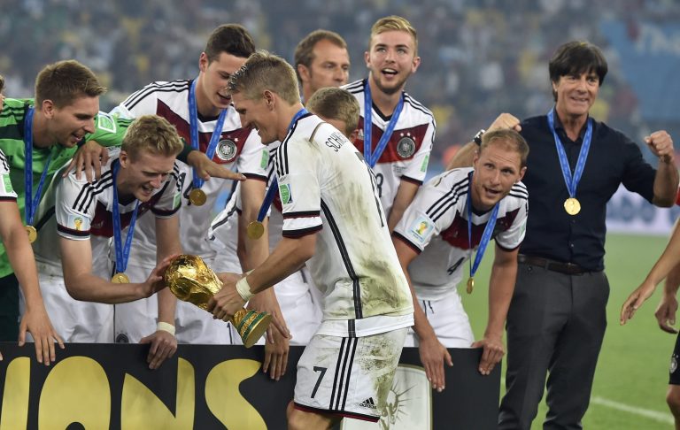 Germany's Andre Schuerrle touches the trophy held by Bastian Schweinsteiger as they celebrate after the World Cup final soccer match between Germany and Argentina at the Maracana Stadium in Rio de Janeiro, Brazil, Sunday, July 13, 2014. Germany won the match 1-0.   (AP Photo/Martin Meissner)