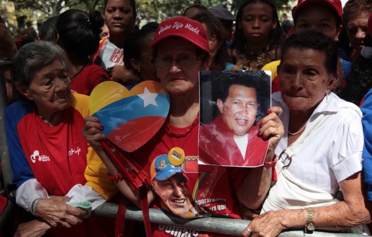   A woman holds a picture of Venezuela's President Hugo Chavez as supporters gather at Simon Bolivar square in Caracas,Venezuela, Sunday Dec. 9, 2012. Chavez is to return to Cuba Sunday for another surgery in his battle against cancer, which has led him to speak publicly of a successor for the first time. Chavez said Saturday that if there are 