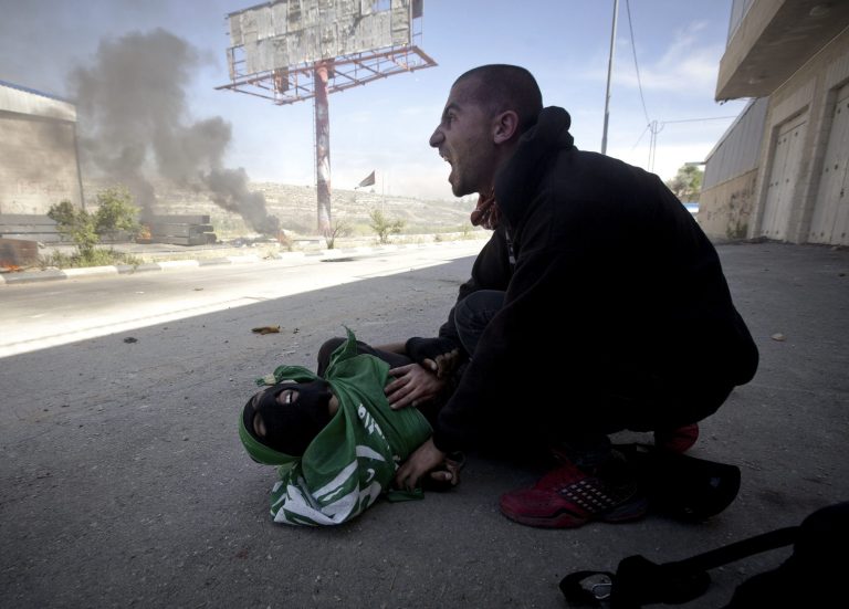 A Palestinian man shouts for help moments after Palestinian teen, Mohammad Abu Daher, on the ground, was shot to death by Israeli troops near the West Bank city of Ramallah, Thursday, May 15, 2014. Medical officials say Israeli troops have shot dead two Palestinian teens in a West Bank clash that erupted after Palestinians marked the anniversary of their uprooting in the war over Israel's 1948 creation. Officials at Ramallah Hospital say the two, ages 15 and 17, were shot in the upper body by live fire. (AP Photo/Majdi Mohammed)