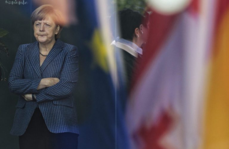 German Chancellor Angela Merkel stands behind a window with  reflection of flags,  as she waits for the arrival of Georgia's Prime Minister Irakli Garibashvili for talks at the chancellery in Berlin, Monday, June 2, 2014.  (AP Photo/Markus Schreiber),