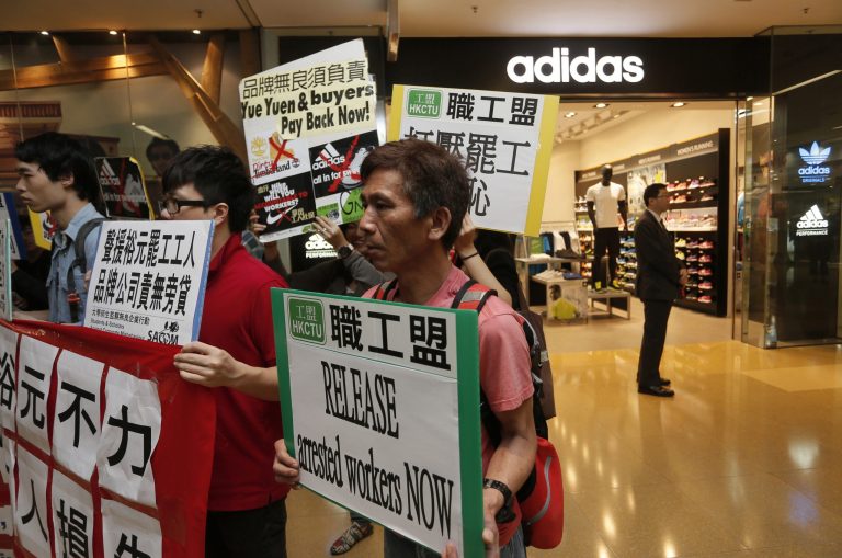 FILE - In this April 24, 2014 file photo, protesters from labor organizations hold banners and placards during a protest to support workers on strike at Yue Yuen Industrial Holdings Ltd. outside a Adidas shop at a shopping mall in Hong Kong. Most of the tens of thousands of workers who were striking at a massive Chinese shoe factory complex have returned to the job, labor activists said Saturday, April 26, enabling Adidas to resume production there. The Germany-based athletic wear giant said workers returned Friday to its factory run by Taiwanese-owned Yue Yuen Industrial Holdings Ltd., the world's largest manufacturer of athletic shoes. (AP Photo/Vincent Yu, File)