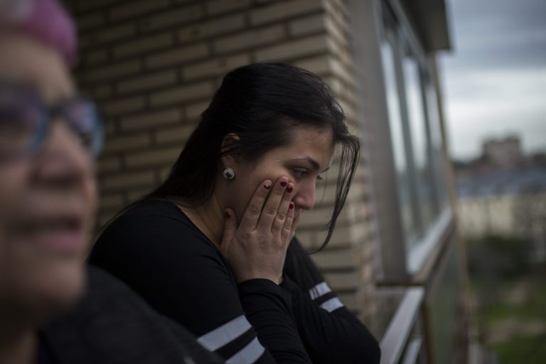 Carolina Salazar Fernandez, 23 years old, right, accompanied by a housing rights activist, left, looks at the police arriving to evict her in Madrid, Spain, Thursday, Feb. 27, 2014. Carolina Salazar Fernandez, is a single mother of two children: Jesus, 3 years old, and Abraham, 6 years old. Her only income it is a state benefit of 530 euros ($ 723). She has occupied an empty foreclosed apartment owned by SAREB bank in February 2013. She tries to negotiate to pay a low protected rent, since her income it is not enough to rent an apartment and support the family at the same time. The eviction was finally postponed with the help of housing rights' activists. SAREB, called 
