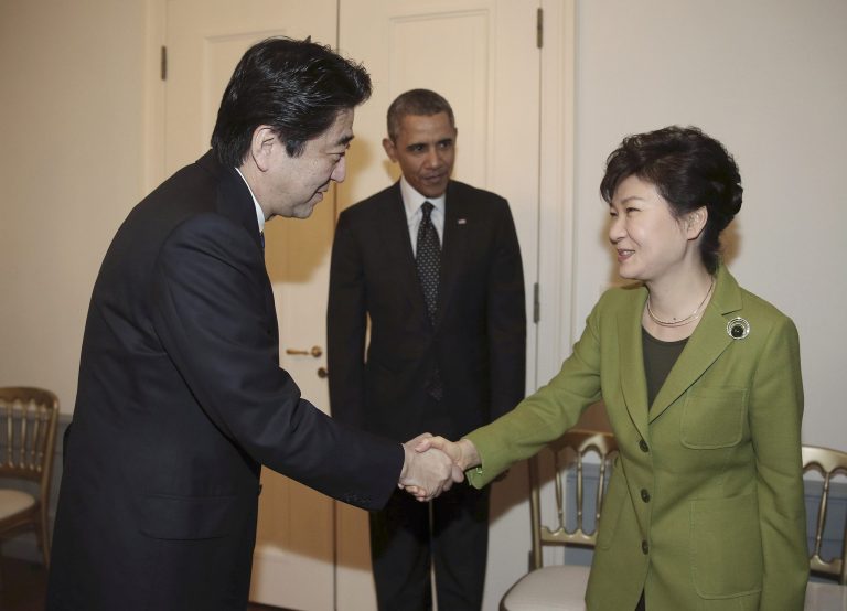 South Korean President Park Geun-hye, right, shakes hands with Japanese Prime Minister Shinzo Abe, left, as U.S. President Barack Obama looks on before their trilateral meeting at the U.S. Ambassador's Residence in the Hague, Netherlands, Tuesday, March 25, 2014. (AP Photo/Yonhap, Do Kwang-hwan)  KOREA OUT