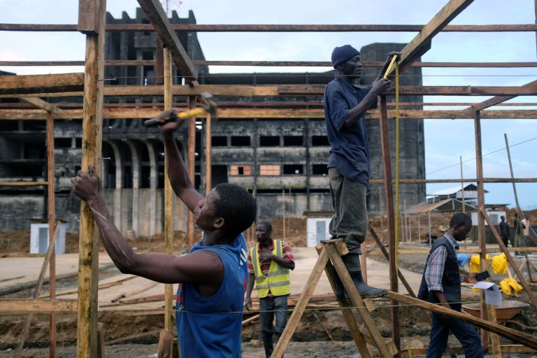 Construction workers build an Ebola isolation and treatment center in front of a unfinished and abandoned government building in Monrovia, Liberia, Thursday Sept. 25, 2014.  The center , due to open within two weeks, will add 200 beds to existing centers. The outbreak of Ebola has overwhelmed the weak health systems of some of the world's poorest countries: There aren't enough doctors and nurses or even clinics to treat the spiraling number of cases.(AP Photo/Jerome Delay)
