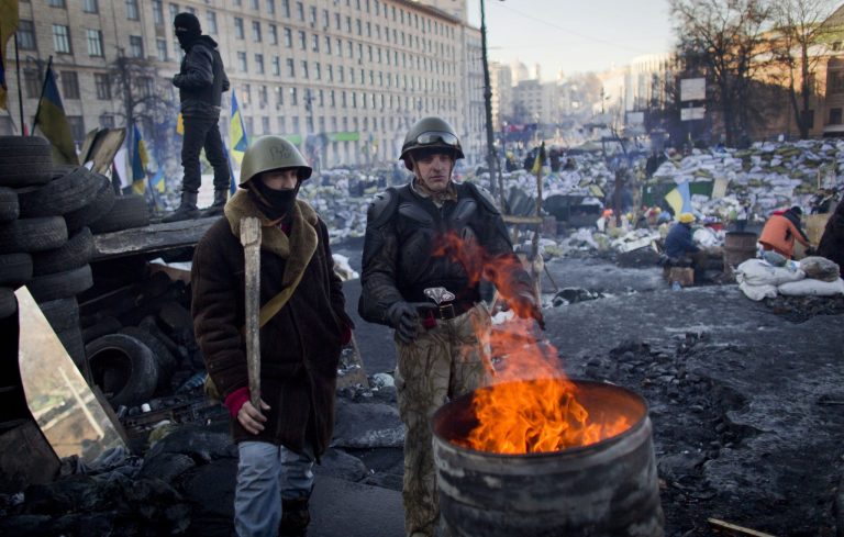 Anti-government protesters warm themselves as they man a barricade in central Kiev, Ukraine, Tuesday, Feb. 4, 2014. Leaders of the anti-government protests that have gripped Ukraine's capital for more than two months say they will seek constitutional changes that will weaken the president's powers. (AP Photo/Darko Bandic)