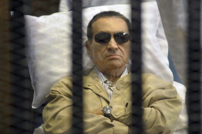   FILE - In this June 2, 2012 file photo, Egypt's ex-President Hosni Mubarak lies on a gurney inside a barred cage in the police academy courthouse in Cairo, during a hearing in which he was sentenced to life in prison for his role in the killing of protesters during the revolution in the spring of 2011. An Egyptian security official says Mubarak has been slipping in and out of consciousness, more than a week after he was transferred to a hospital inside a Cairo prison to serve his life sentence. The official says Mubarak's wife, former first lady Suzanne Mubarak, and her two daughters-in-law were visiting him in prison Sunday, June 10, 2012, after rumors circulated that he had died. (AP Photo, File)  