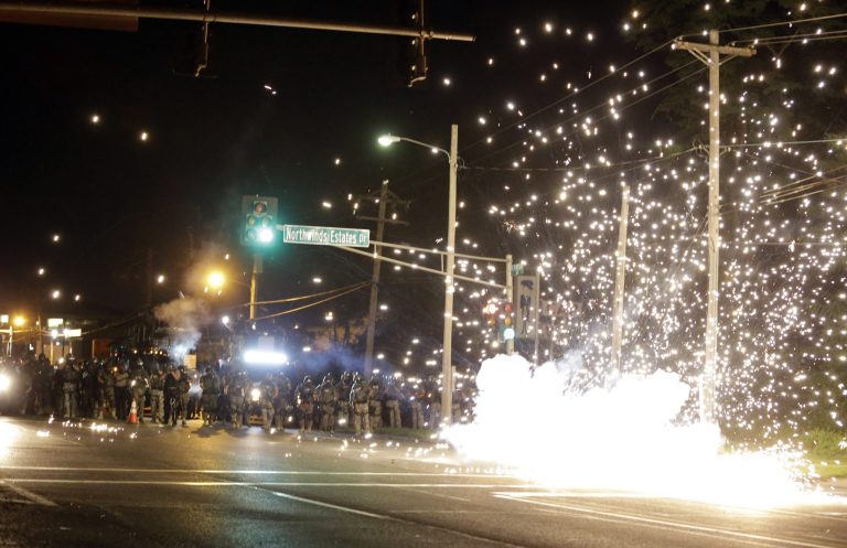 A device deployed by police goes off in the street as police and protesters clash Wednesday, Aug. 13, 2014, in Ferguson, Mo. Authorities in the St. Louis suburb where an unarmed black teen was shot and killed by a police officer have used tear gas to try to disperse protesters after flaming projectiles were thrown from the crowd. (AP Photo/Jeff Roberson)