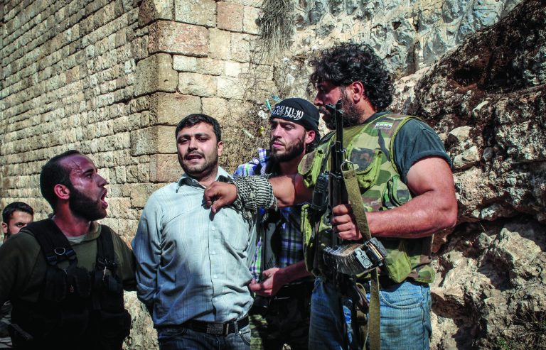 In this Tuesday, Oct. 30, 2012 photo, Free Syrian Army fighters shout at a captured suspected pro-Bashar Assad fighter in the town of Harem, Syria. Rebels say the man was killed shortly after this picture. Despite two weeks of attacking a Roman-era citadel in which pro-Assad militia are dug in, the rebels failed to secure the town. (AP Photo/Mustafa Karali)