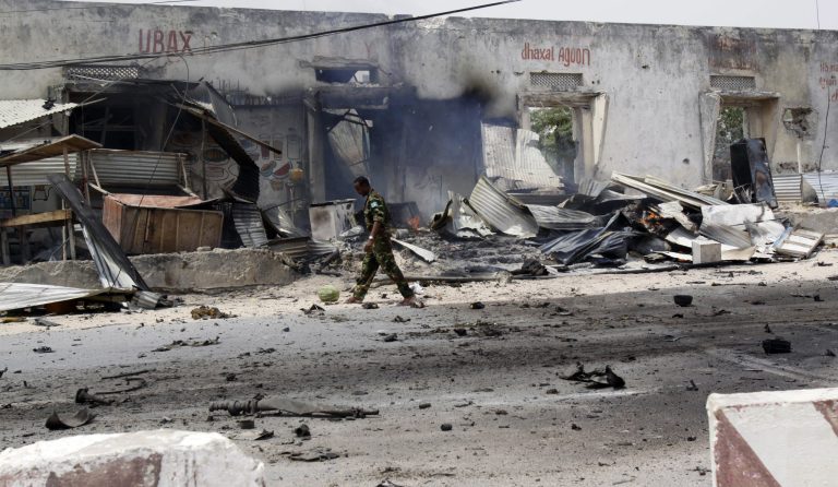A Somali soldier walks near the destroyed building in Mogadishu, Somali , Thursday, Feb. 13, 2014. Police in Somalia say a car bomb explosion near Mogadishu's airport has killed at least three people and wounded five.  Police Capt. Mohamed Hussein said the blast Thursday was detonated by remote control at the city's busy airport junction. He blamed the militant group al-Shabab. Hussein said three people were killed.(AP Photo?Farah Abdi Warsameh)