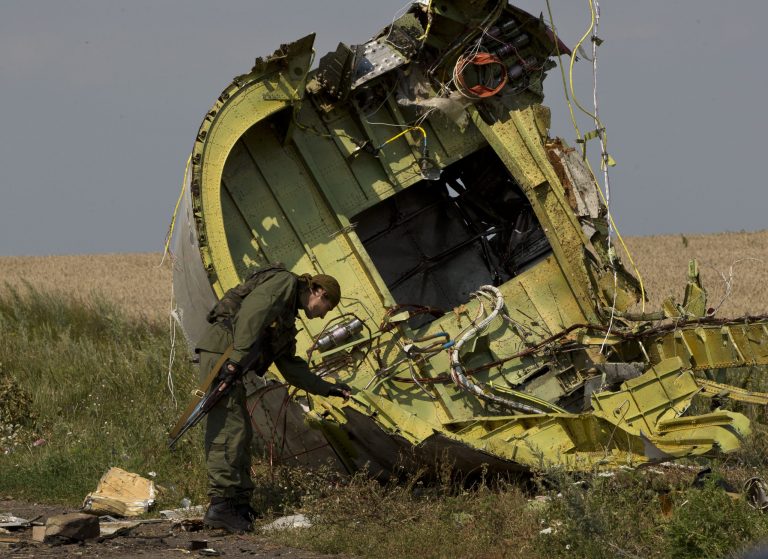 FILE - In this July 22, 2014 file photo, a pro-Russian rebel touches the MH17 wreckage at the crash site of Malaysia Airlines Flight 17, near the village of Hrabove, eastern Ukraine. Japan's top government spokesman said Monday, July 28 that the country is stepping up sanctions against Russia over the unrest in Ukraine. The sanctions include the freezing of assets held in Japan by individuals and groups supporting the separation of Crimea from Ukraine, as well as a ban on Crimean imports, Chief Cabinet Secretary Yoshihide Suga said. The move follows the July 17 downing of Malaysia Airlines Flight 17 in eastern Ukraine. (AP Photo/Vadim Ghirda, File)
