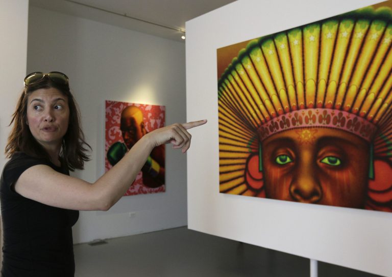 Vesna K. Stelcer, board chair of the Ed Paschke Foundation, explains a painting titled American Sueno on Friday, June 20, 2014 in Chicago. The painting was created by Ed Paschke and will be on display at the Ed Paschke Art Center starting on Sunday, June 22.  (AP Photo/Stacy Thacker)