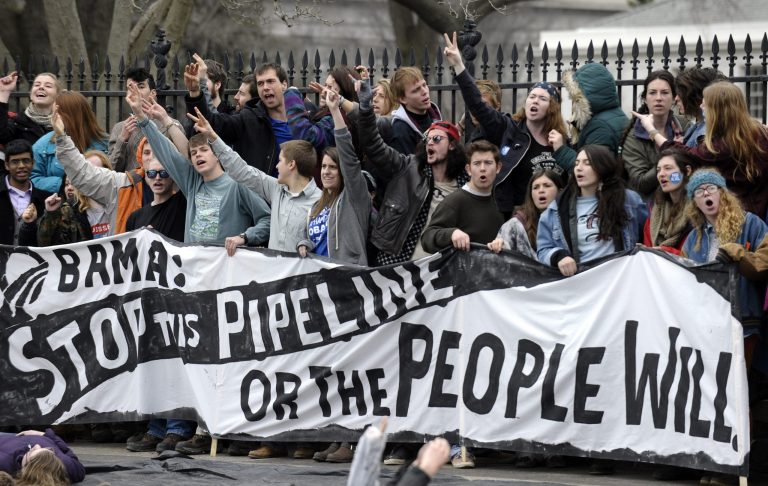 Several hundred students and youth who marched from Georgetown University to the White House to protest the Keystone XL Pipeline yell as they wait to be arrested outside the White House in Washington, Sunday, March 2, 2014. (AP Photo/Susan Walsh)
