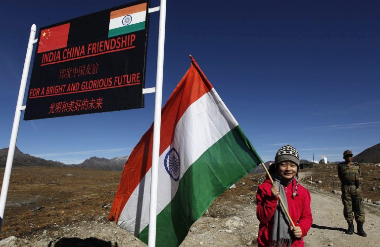 FILE - In this Oct. 21, 2012 file photo, an Indian girl poses for photos with an Indian flag at the Indo China border in Bumla at an altitude of 15,700 feet (4,700 meters) above sea level in Arunachal Pradesh, India. For more than 50 years, it has pitted India against China - a smoldering dispute over who should control a swath of land larger than Austria. Two militaries have skirmished. A brief, bloody war has been fought. And today, thousands of soldiers from both countries sit deployed along their shared frontier, doing little but watching each other.  (AP Photo/Anupam Nath, File)