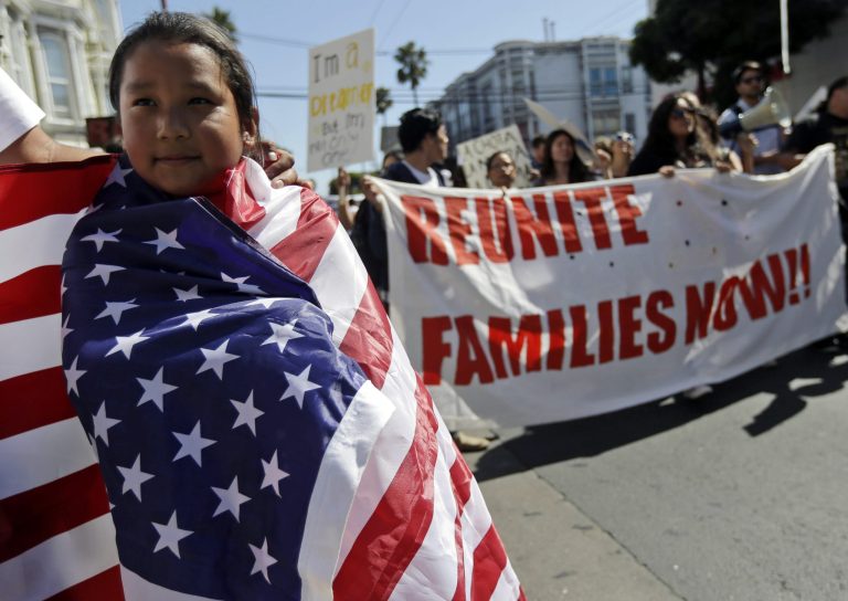Maria Fernanda Medina, 7, wraps herself in a United States flag as she marches with her father, Jorge, during a May Day demonstration in San Francisco, Wednesday, May 1, 2013.  Demonstrators demanded an overhaul of immigration laws Wednesday in an annual, nationwide ritual that carried a special sense of urgency as Congress considers sweeping legislation that would bring many of the estimated 11 million people living in the U.S. illegally out of the shadows. (AP Photo/Marcio Jose Sanchez)
