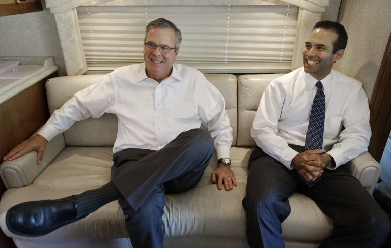 Former Florida Gov. Jeb Bush, left, and his his son George P. Bush smile as they sit on a campaign bus during an interview Tuesday, Oct. 14, 2014, in Abilene, Texas. (AP Photo/LM Otero)
