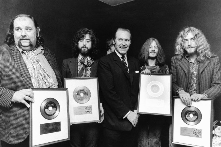Three members of Led Zeppelin accept gold records representing sales of one million copies of each of their records in London in 1970. The members are, left to right, guitarist Jimmy Page, bassist John Paul Jones and singer Robert Plant. At far left, wearing a checked jacket and an ascot, is the band's manager, Peter Grant. The decidedly unhip gent in the dark suit in the center is Anthony Grant, then parliamentary secretary for Britain's Board of Trade. (AP Photo)