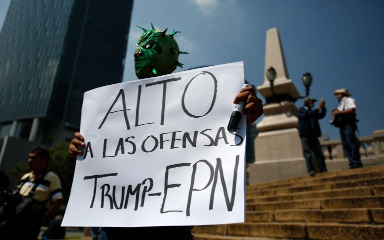 Donald Trump is visiting Mexico at the invitation of the nation's president. Above, a man wears a Mexican wrestling mask and holds a sign reading in Spanish; 