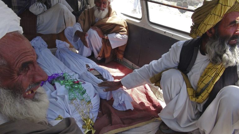 Elderly Afghan men sit with the covered bodies of three children killed in an apparent NATO raid in Logar province, south of Kabul, Afghanistan on Wednesday, June, 6, 2012. Afghan officials and residents say a pre-dawn NATO airstrike aimed at militants in eastern Afghanistan killed civilians celebrating a wedding, including women and children.