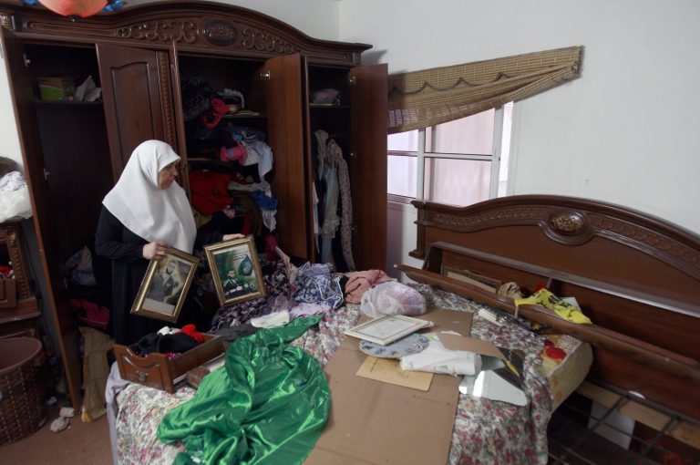 Palestinian Asmaa Abu El-Heija holds pictures of two of her sons as she cleans up her home after a raid by Israeli troops as the army continues feverish searches for three missing Israeli teens, in the West Bank refugee camp of Jenin, Monday, June 23, 2014. El-Heija, who was imprisoned in Israeli jail, has a husband and three sons currently being held, while a fourth son, Hamza, who was a member of the Hamas military wing, the Qassam Brigades, was killed a few months ago by Israeli troops. Israel has arrested more than 350 Palestinians, most affiliated with the Islamic militant Hamas, and raided some 1,600 locations in their search for the three teens. (AP Photo/Mohammed Ballas)