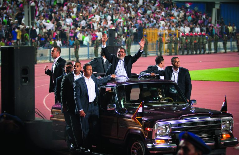 Egyptian President Mohammed Morsi, waves to the crowd gathered in a stadium upon his arrival for a speech on the 6th of October national holiday marking the 1973 war with Israel, Cairo, Egypt, Saturday, Oct. 6, 2012.(AP Photo/Khalil Hamra)