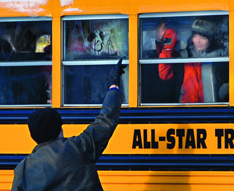 A man waves to a child on a bus on the first day of classes after the holiday break, in Newtown, Conn.,Wednesday, Jan. 2, 2013. Nearly three weeks after the shooting rampage at Sandy Hook Elementary School in Newtown, students and teachers from the school will return to class Thursday in the neighboring town of Monroe. (AP Photo/Jessica Hill)