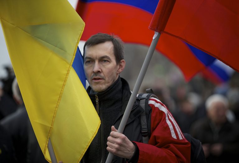 A demonstrator carries both Russian and Ukrainian flags during a march to oppose Vladimir Putin's policies in Ukraine, in Moscow on Saturday. (AP Photo/Alexander Zemlianichenko)