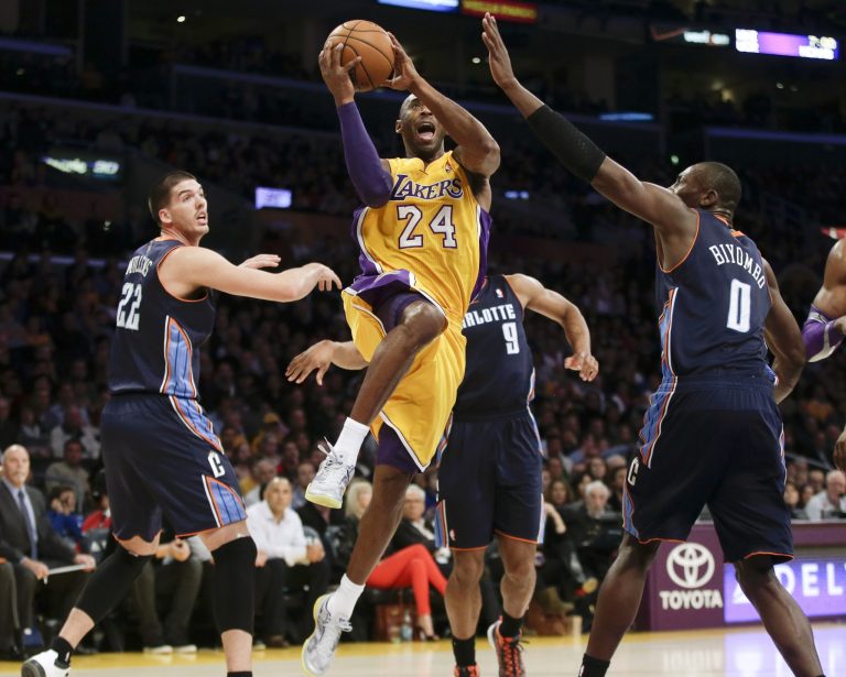   Los Angeles Lakers' Kobe Bryant drives to the basket between Charlotte Bobcats' Byron Mullens, left, and Bismack Biyombo during the first half of an NBA basketball game in Los Angeles, Tuesday, Dec. 18, 2012. (AP Photo/Chris Carlson)  