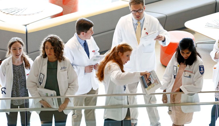 In this 2017 photo, medical students speak among themselves as they watch the dedication ceremony for the new University of Mississippi School of Medicine in Jackson, Miss. Despite initiatives to improve the diversity of matriculating classes, medical school is increasingly for the children of the rich and well-educated. (AP Photo/Rogelio V. Solis)