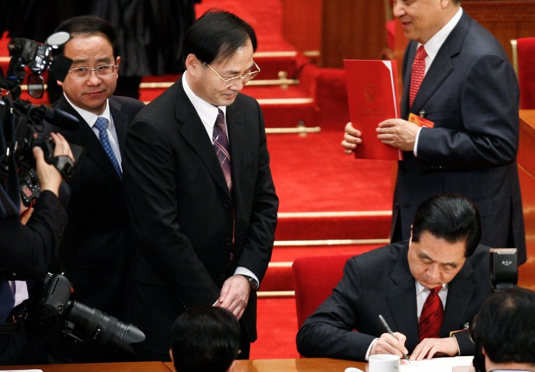 In this photo taken on March 14, 2010, Ling Jihua, a loyal aide and confidante to President Hu Jintao, left, looks as Chinese President Hu Jintao, bottom right, signs a document after attending a closing ceremony of the National People's Congress at the Great Hall of the People in Beijing. Chinaâs hopes for a smooth, once-a-decade political transition have been shaken by a lurid new scandal involving the death of a senior officialâs son who crashed during what may have been sex games in a speeding Ferrari. Details of the March accident in Beijing, which allegedly also left two young women injured, have stayed under wraps in China but are leaking out via media in Hong Kong. The media blackout underscores official fears that the public will be outraged by another instance of excess and recklessness among Chinaâs power elites. (AP Photo/Andy Wong)