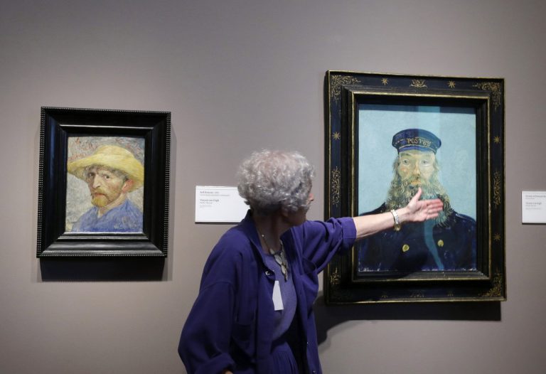 Detroit Institute of Arts docent Lea Schelke points out details in the Portrait of Postman Roulin, by Vincent van Gogh, displayed at the museum in Detroit on June 13. (AP Photo/Carlos Osorio, File)