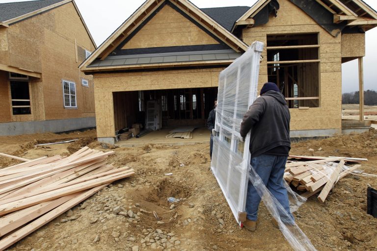   In this Feb. 8, 2012 photo, two workers carry a window for a home under construction in a new subdivision by Toll Brothers, in Yardley, Pa. Toll Brothers says its fiscal fourth-quarter net income in 2012 soared, helped by a large income tax benefit and a 48 percent rise in revenue. The luxury homebuilder delivered more homes and its order backlog increased. (AP Photo/Alex Brandon)  