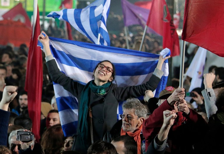 A supporter of Alexis Tsipras leader of Syriza left-wing party holds the Greek flag during a rally outside Athens University Headquarters, Sunday. (AP/Lefteris Pitarakis)