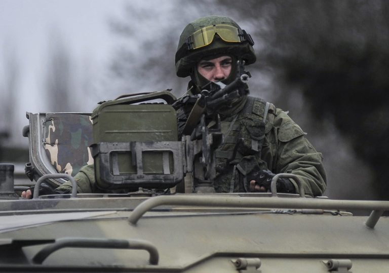 A man in unmarked uniform looks from atop of a military vehicle while standing guard as troops taking control the the Coast Guard offices in Balaklava, outskirts of Sevastopol, Ukraine, Saturday, March 1, 2014. An emblem on one of the vehicles and their number plates identify them as belonging to the Russian military. Ukrainian officials have accused Russia of sending new troops into Crimea, a strategic Russia-speaking region that hosts a major Russian navy base. The Kremlin hasn't responded to the accusations, but Russian lawmakers urged Putin to act to protect Russians in Crimea. (AP Photo/Andrew Lubimov)