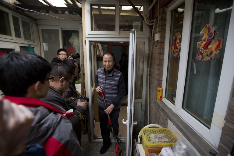 Guan Shiyue, a 69-year-old retiree who lives in a small, sparsely furnished home is mobbed by journalists after he was visited by Chinese President Xi Jinping in Beijing, China, Tuesday, Feb. 25, 2014. Chinese President Xi Jinping braved Beijingâs choking smog Tuesday, making an unannounced visit to a trendy alley and sitting with residents in his latest public relations effort to be seen as a man of the people. (AP Photo/Ng Han Guan)