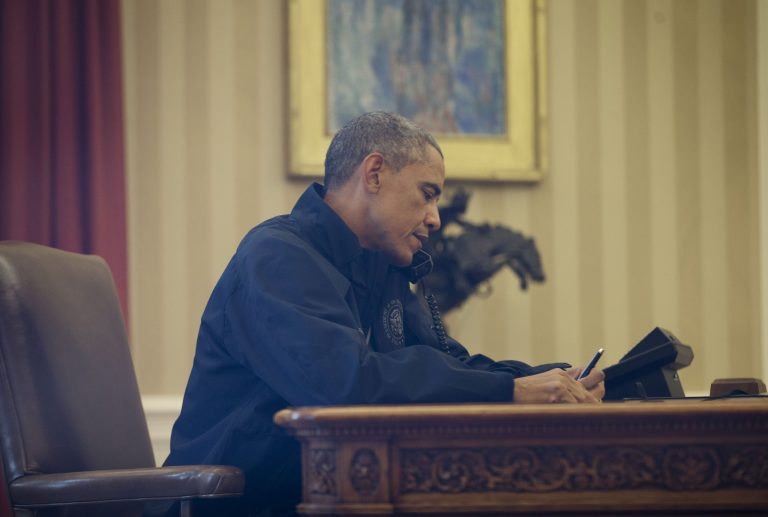 Seen through the window of his Oval Office, President Barack Obama talks with Health and Human Services Secretary Sylvia Burwell for an update on the new Ebola virus diagnosis in Dallas at the White House in Washington, Sunday, Oct. 12, 2014. (AP Photo/Pablo Martinez Monsivais)
