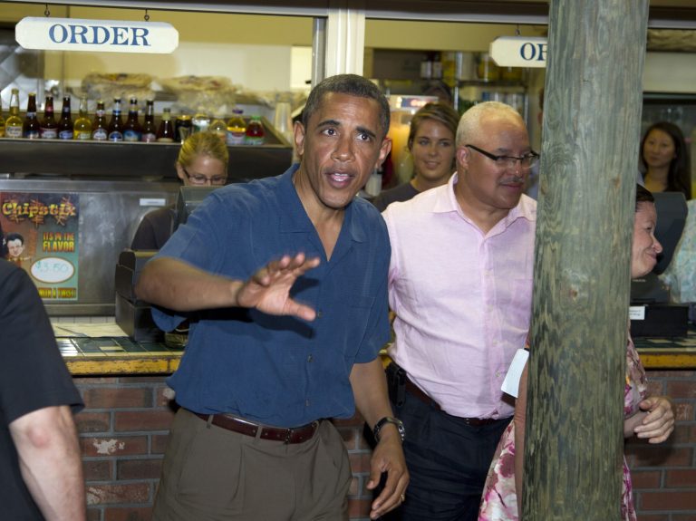 President Obama waves to people as the stops at the take out window at Nancy's Restaurant in Oak Bluffs on Martha's Vineyard, Mass., with Eric Whitaker, center and Valerie Jarrett, right, partially obscured, Sunday, Aug. 21, 2011, during a family vacation. (AP/Carolyn Kaster)