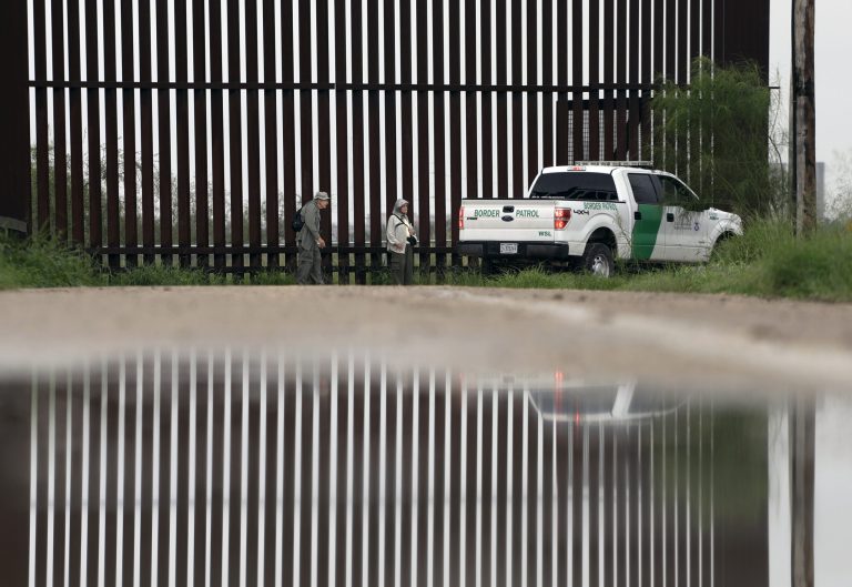 In this Sunday, Nov. 13, 2016, photo, a U.S. Customs and Border Patrol agent passes birdwatchers Rayborn and Nancy Hill along a section of border wall in Hidalgo, Texas. The idea of a concrete wall spanning the entire 1,954-mile southwest frontier collides head-on with multiple realities, like a looping Rio Grande, fierce local resistance, and cost. (AP Photo/Eric Gay)