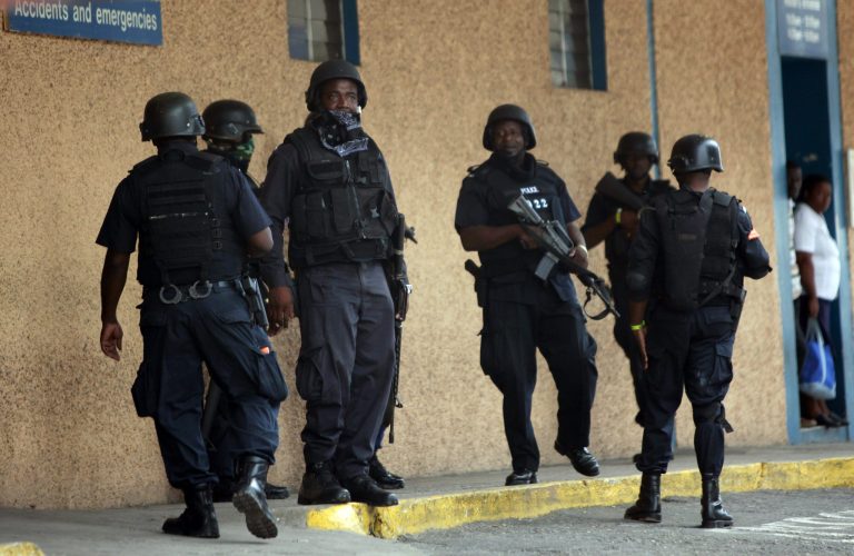 FILE - In this May 26, 2010 file photo, police officers stand guard near the emergency room entrance of the national hospital in Kingston, Jamaica. National Security Minister Peter Bunting announced Thursday, Jan. 23, 2014, that some Jamaican police units will soon be wearing video cameras on their uniforms in part to encourage officers to use appropriate force and perhaps curb high rates of killings by law enforcers in a Caribbean country where they have long been accused of trigger-happy tactics. (AP Photo/Rodrigo Abd, File)