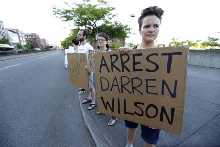 Protester Hana Kato, of Tacoma, Wash., holds a sign that reads 