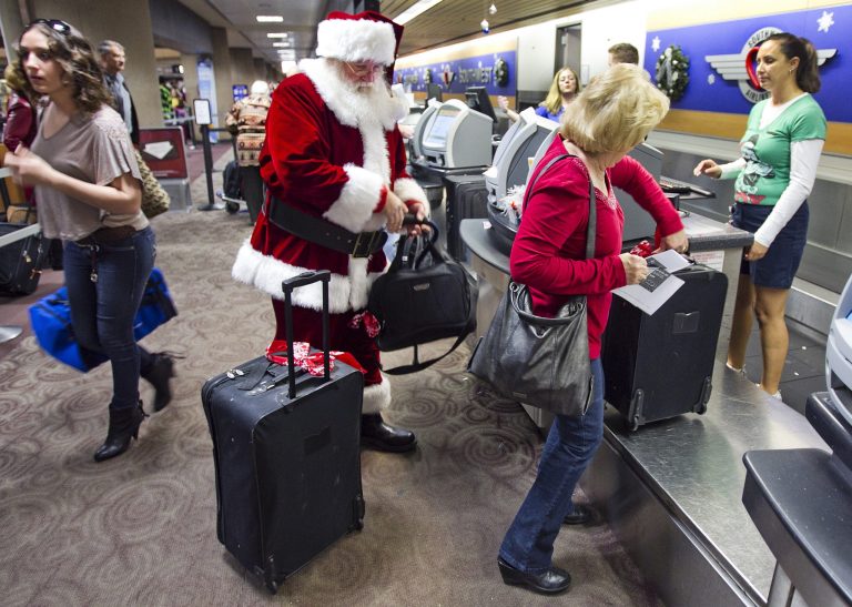   FILE - In this Wednesday, 21, 2011, file photo, holiday travelers, including Donald Occimio of Mesa, Ariz., dressed as Santa Claus, and his wife Diane check in with customer service agent Angelee Arciniega, right, for their Southwest Airlines flight at the Terminal 4 ticketing area at Sky Harbor International Airport, in Phoenix. The 2012 Christmas travel season could be the busiest in six years, with AAA predicting that 93.3 million Americans will hit the road. That's 1.6 percent more than last year and just 400,000 people shy of the 2006 record. (AP Photo/The Arizona Republic, Tom Tingle) MARICOPA COUNTY OUT; MAGS OUT; NO SALES  