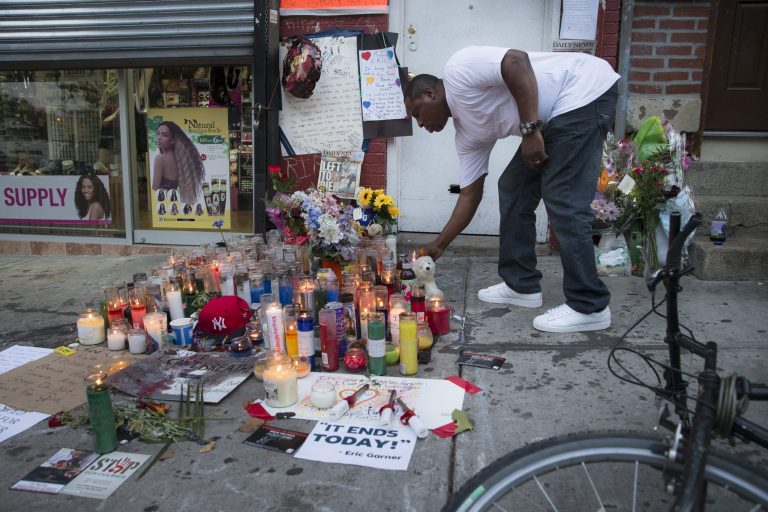 A mourner places a candle at a memorial for Eric Garner, a Staten Island man who died while being arrested by New York City police Tuesday in New York. (AP/John Minchillo)