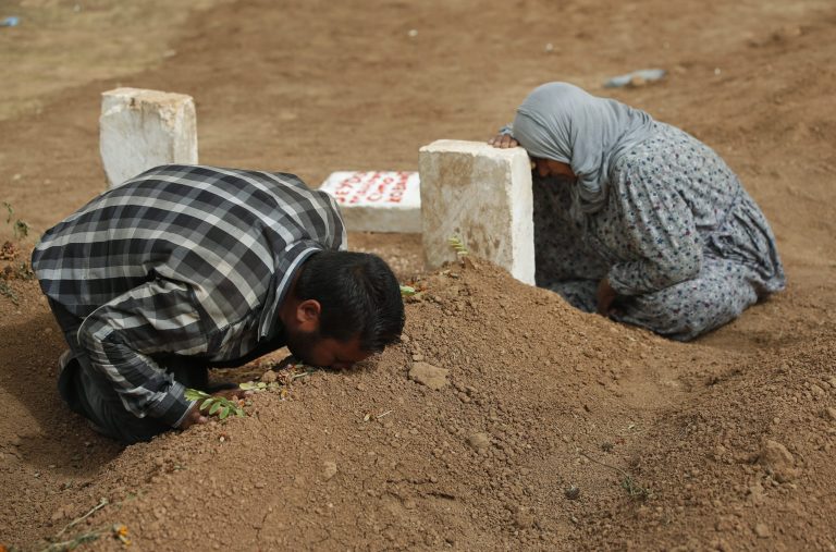 FILE - In this  Saturday, Oct. 11, 2014 file photo, Kurdish Rabia Ali, right, accompanied by her son Ali Mehmud, mourn at the grave of her son Seydo Mehmud 'Curo' , a Kurdish fighter, who was killed in the fighting with the militants of the Islamic State group in Kobani, Syria, and was buried at a cemetery in Suruc, Turkey. No one contests that the U.S.-led coalition has conducted more than 40 airstrikes against the militants besieging Kobani, nor that Turkey has granted refuge to more than 200,000 people who have flooded across the border to escape the offensive. But Kurds say that both countries - and the international community in general - should be doing more to help save Kobani from the fanatical militants who have massacred and beheaded their enemies across Syria and Iraq. (AP Photo/Lefteris Pitarakis, File)
