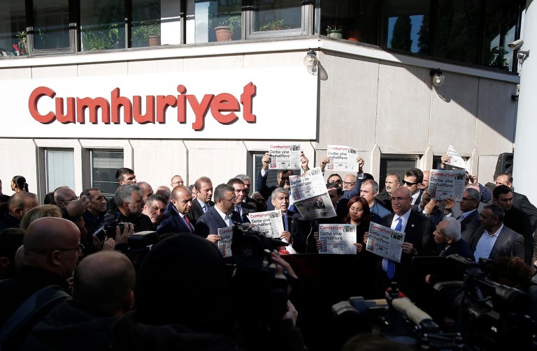 Journalists and lawmakers hold copies of the latest Cumhuriyet newspaper outside its Istanbul headquarters after police detained chief editor Murat Sabuncu and two columnists of Turkey's opposition Cumhuriyet and had warrants to detain 10 other senior staff members, in Istanbul. (AP Photo/Emrah Gurel)