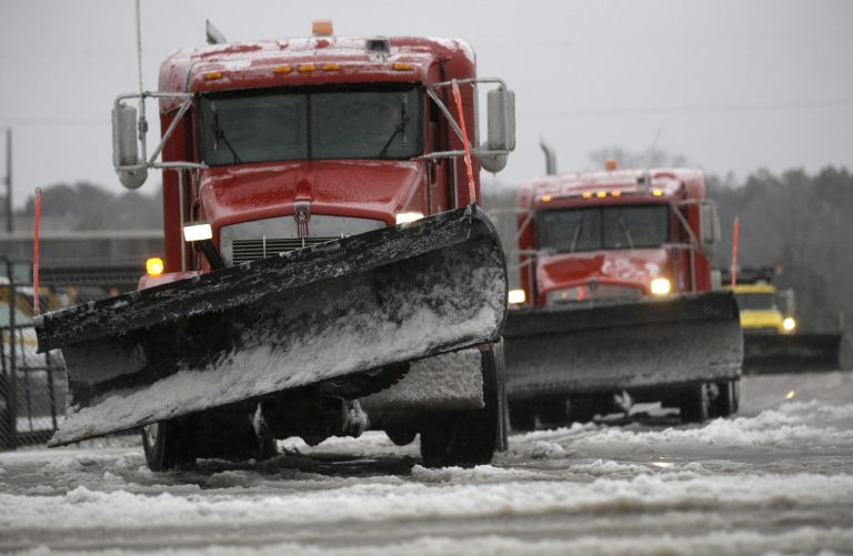 Salt trucks and road plows prepare to treat more roads as they leave the Department of Transportation location on Trinity Road in Raleigh, N.C., Friday, Jan. 22, 2016. A winter storm began dumping snow on the southern and eastern United States on Friday, with mass flight cancelations and five states declaring states of emergency. (AP Photo/Gerry Broome)