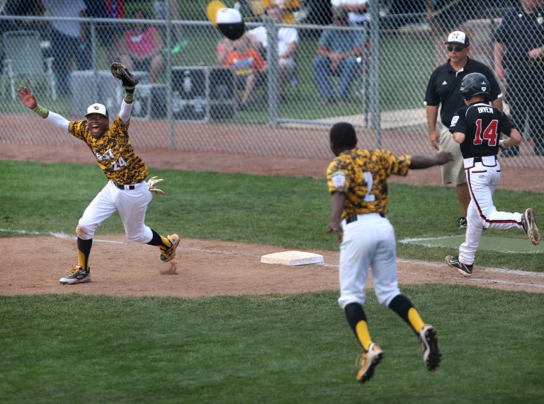 Jackie Robinson West Little League first baseman Trey Hondras, left, and winning pitcher Marquis Jackson start the celebration after the final out of the Chicago team's 12-7 win over New Albany, Ind., in the Little League Central Regional championship baseball game in Lawrence, Ind., on Saturday, Aug. 9, 2014. New Albany's Cooper Biven, right, who was the starting pitcher, runs toward first after grounding out. (AP Photo/The Indianapolis Star, Charlie Nye)