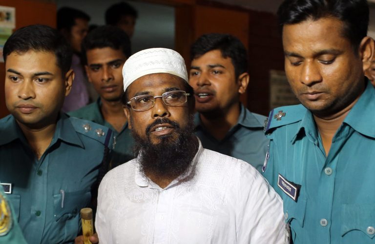 FILE - In this Monday, June 16, 2014 file photo, Mufti Abdul Hannan, center, leader of banned radical group Harkatul Jihad al Islami, stands at a court in Dhaka, Bangladesh. The court on Monday, June 23 sentenced eight people, including the top leader of the banned Islamist group, to death for their roles in a bombing at a New Year's celebration concert 13 years ago. (AP Photo/A.M. Ahad, File)