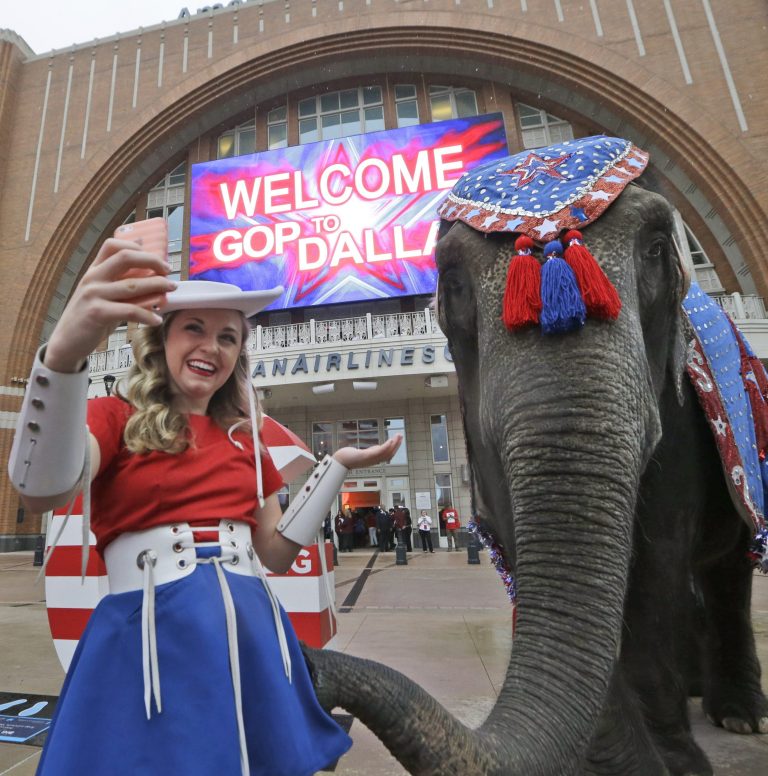 Kilgore Rangerette Chelsea Crawford makes a selfie photo with an elephant in front of the American Airlines Center before a visit by members of the Republican National Committee scouting a 2016 Convention host site in Dallas, Thursday, June 12, 2014. American Airlines Center would serve as the convention site if Dallas' bid is successful. Dallas is competing with Denver, Cleveland and Kansas City. (AP Photo/LM Otero)