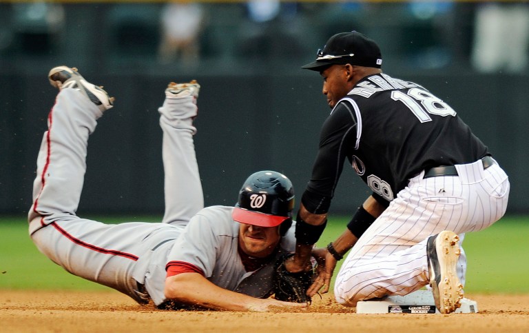 Washington Nationals' Tyler Moore, left, is picked off of second base by Colorado Rockies second baseman Jonathan Herrera, right, in the fourth inning of a baseball game, Thursday, June 28, 2012, in Denver. The Rockies won 11-10 in 11 innings. (AP Photo/Chris Schneider)