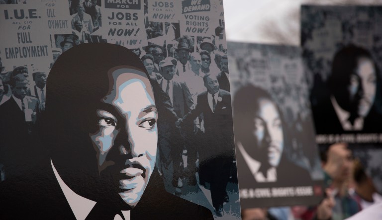 People carry signs as they march following the Rev. Martin Luther King Jr. commemorative service at Ebenezer Baptist Church, Monday, Jan. 16, 2017, in Atlanta. (AP Photo/Branden Camp)